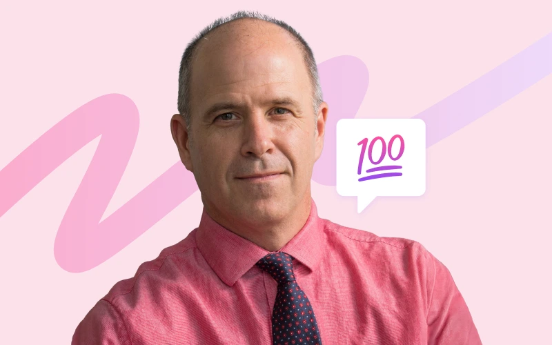 A balding man in a red shirt and patterned tie looks directly at the camera, with a pink background and a speech bubble containing '100' to his right.