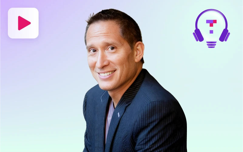 A man with short dark hair and a suit jacket smiles slightly, looking towards the viewer, against a light purple and green gradient background with a play button icon and a lightbulb with headphones graphic.